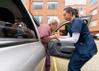 Home caregiver helping a senior woman get out of a car â assisted living concepts