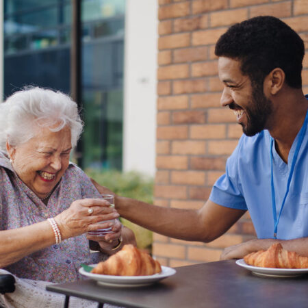 Caregiver having breakfast with his client at a cafe.